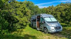 Picture of a camping-van with a sun blind at its windscreen.